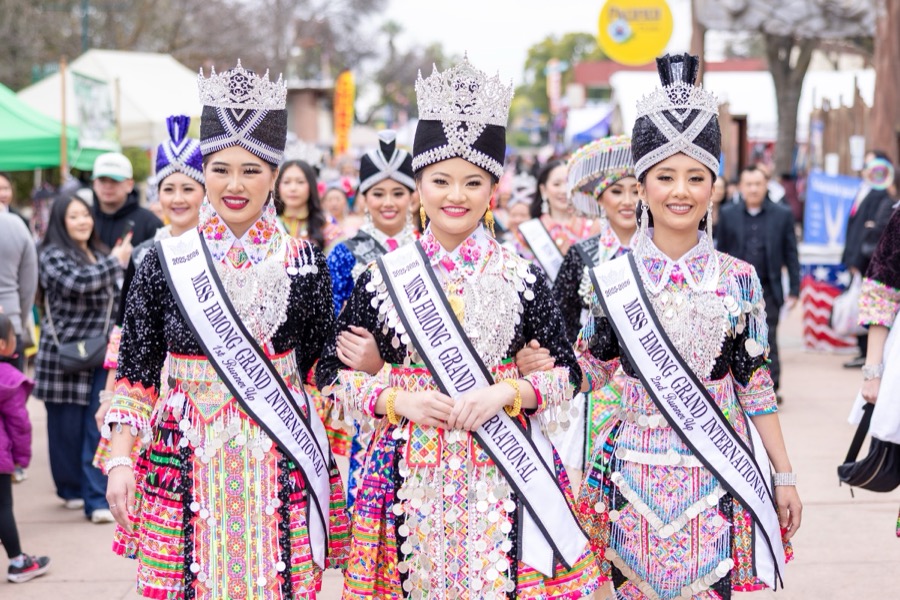 Titleholders in ceremonial dress and silver crowns moving through the festival crowd.